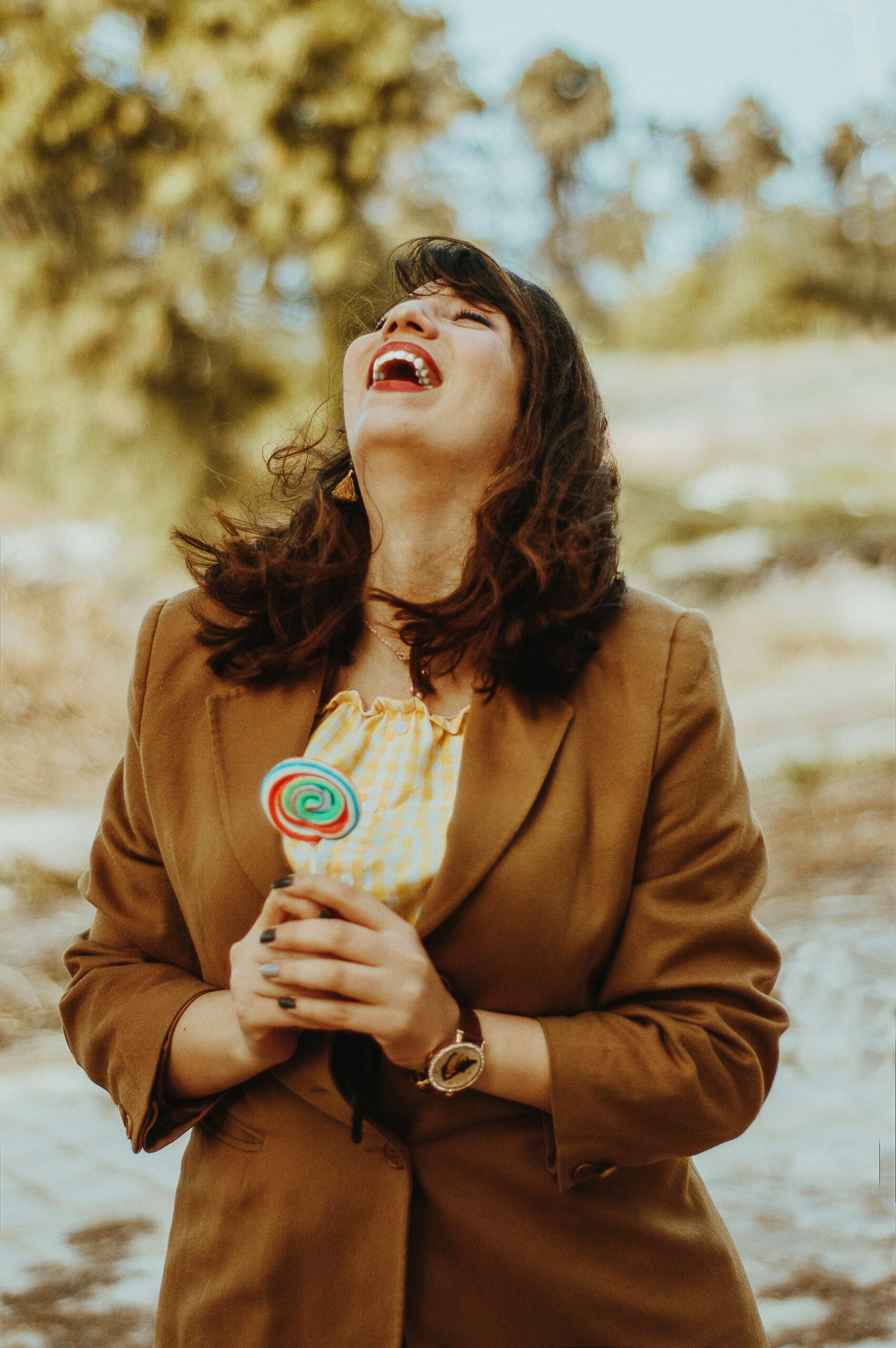 woman laughing with lollipop outdoors